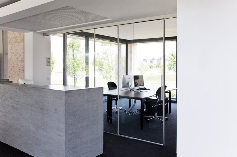 Empfangsbereich im Büro mit Arbeitsplätzen unterteilt durch Schiebetüren mit klarem Schallschutzglas