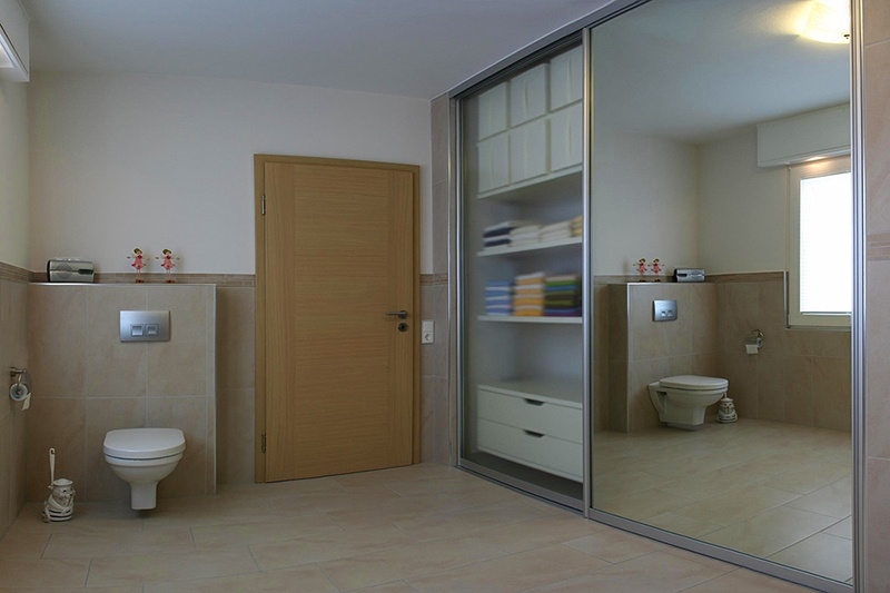 Badezimmer mit Einbauschrank abgedeckt durch große Schiebetür mit Spiegel
