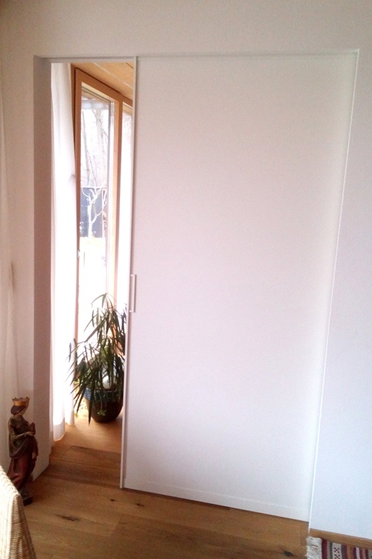 Wohnzimmer und Küche unterteilt durch Holz Schiebetür in einer Wand mit weißem Dekor