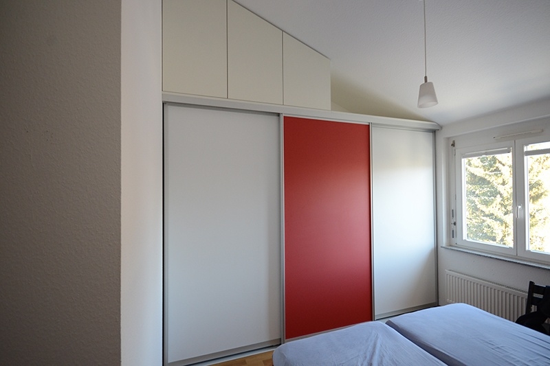 Schlafzimmer und Ankleide unterteilt durch Schiebetüren mit weißem und rotem Dekor