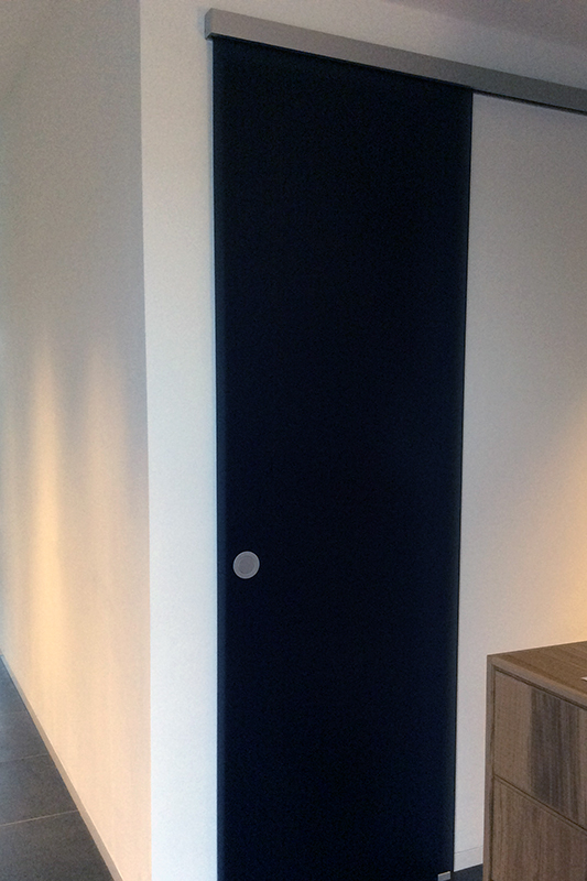 Wohnraum mit Garderobenschrank abgetrennt durch schwarze blickdichte Glasschiebetür