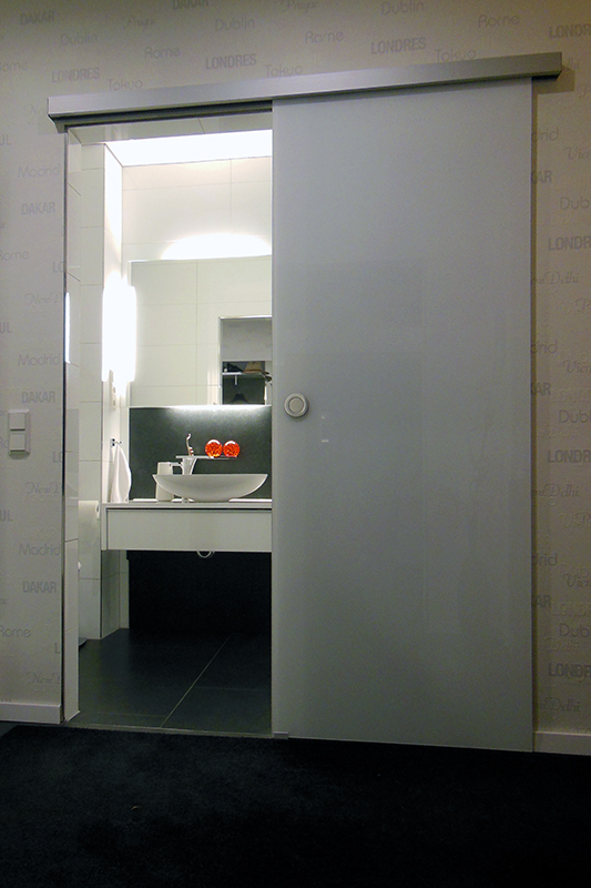 Wohnraum mit Zugang zum Bad unterteilt durch Glasschiebetür aus satiniertem Glas