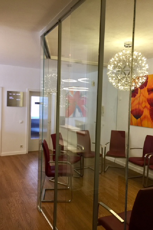 Praxisraum mit Wartezimmer unterteilt durch Glasschiebetür Raumteiler aus klarem Glas